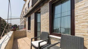 A balcony with wicker furniture, stone walls, and large windows. - Naz Wooden House Inn - Byzantine House (Istanbul)