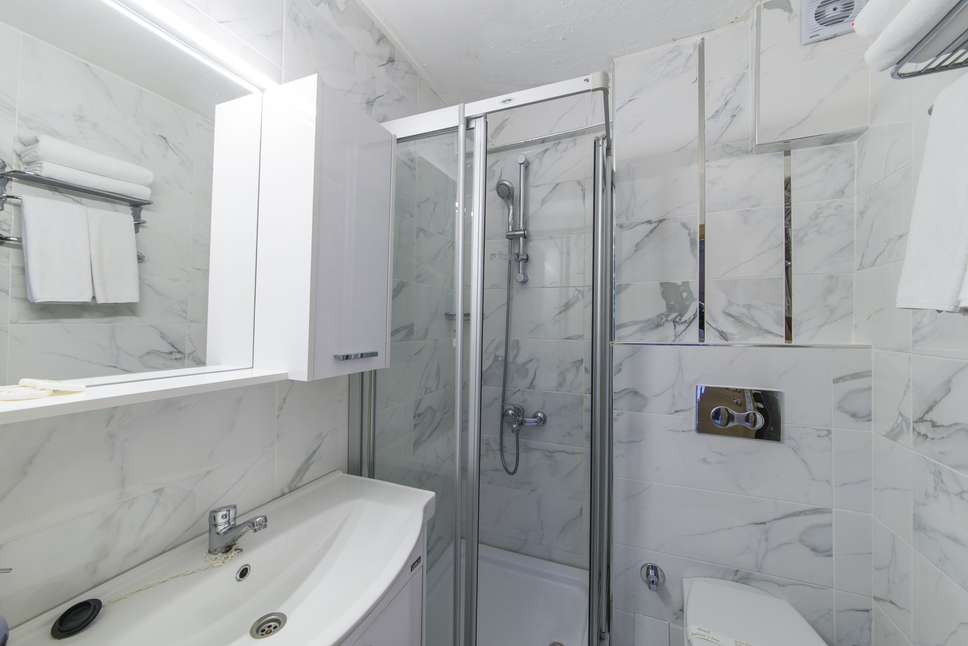 A bathroom with a glass-enclosed shower, a white sink, and a toilet.