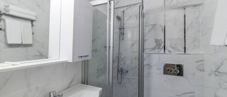 A bathroom with a glass-enclosed shower, a white sink, and a toilet.