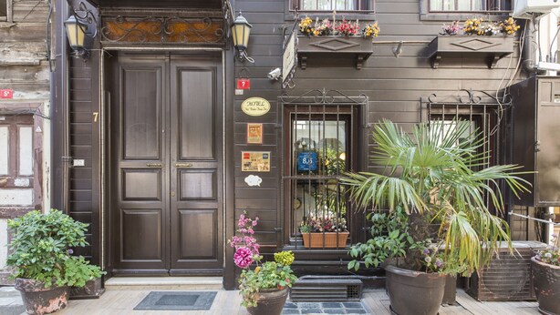 A hotel entrance with a dark wooden door, potted plants, and a sign indicating the hotel name. - Naz Wooden House Inn - Byzantine House (Istanbul)