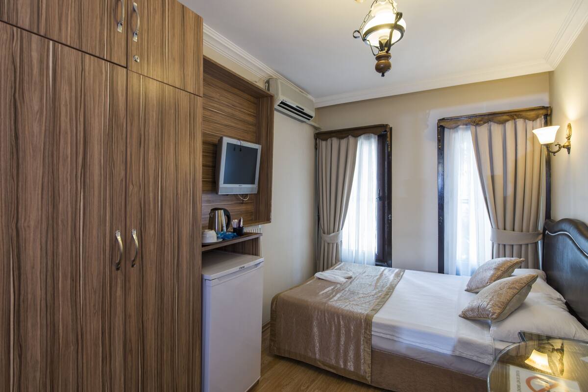 A hotel room with a bed, a television, a desk, and a wardrobe.