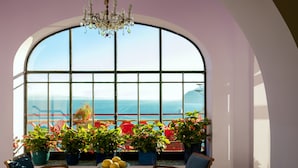 A room with a large arched window, a chandelier, and potted plants. - Hotel Minerva (Sorrento)