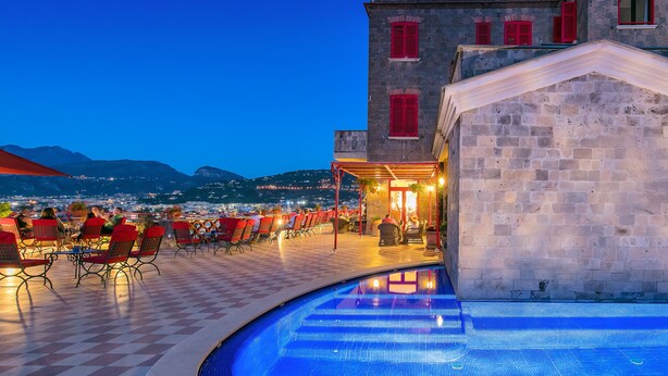 A terrace with a pool, red chairs, and a building with red shutters. - Hotel Minerva (Sorrento)