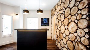 Een receptiegedeelte met een houten wand, twee hanglampen en een lijst met de naam Waterton Glacier Suites.