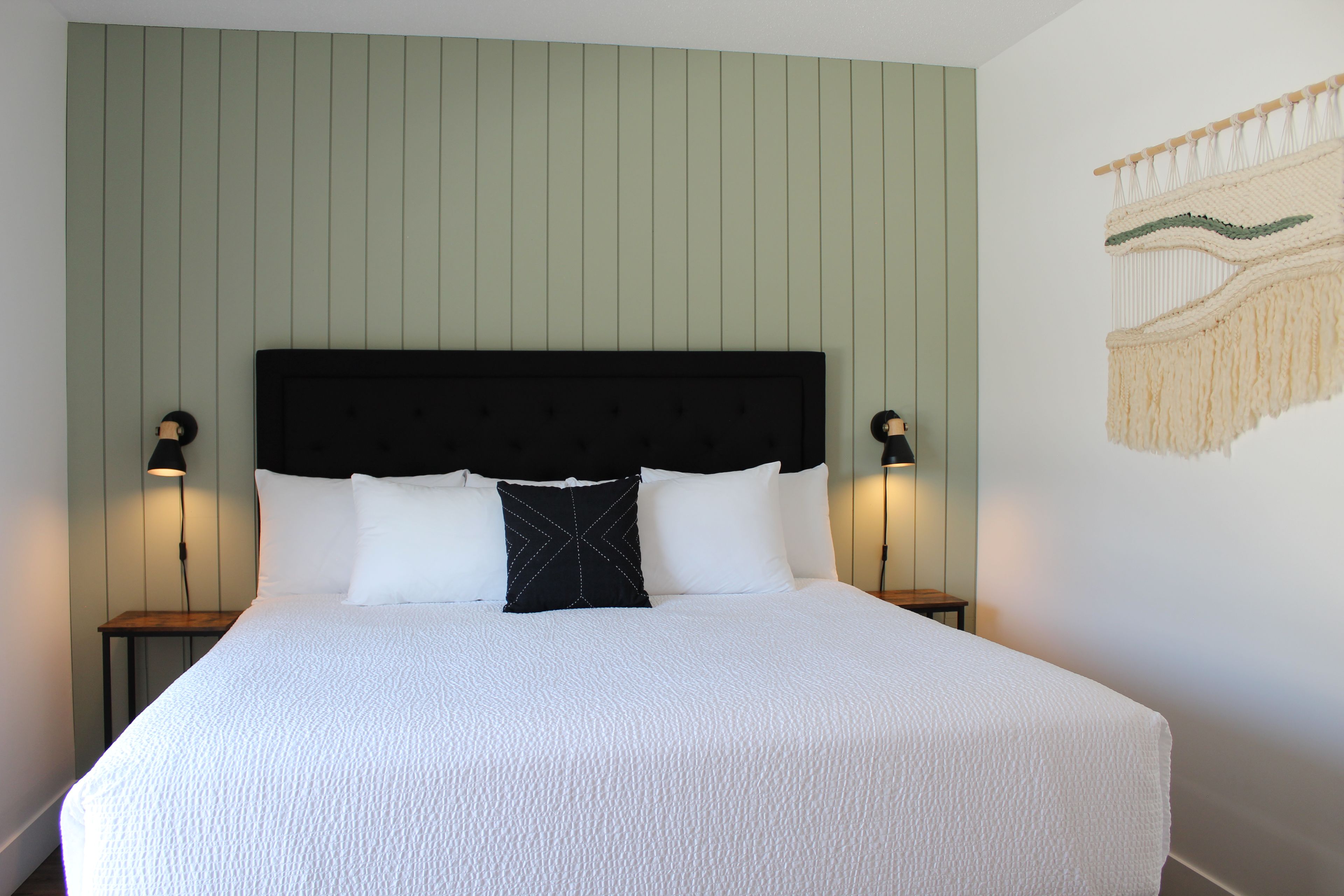 A bed with a white textured bedspread, a black headboard, and two bedside lamps.