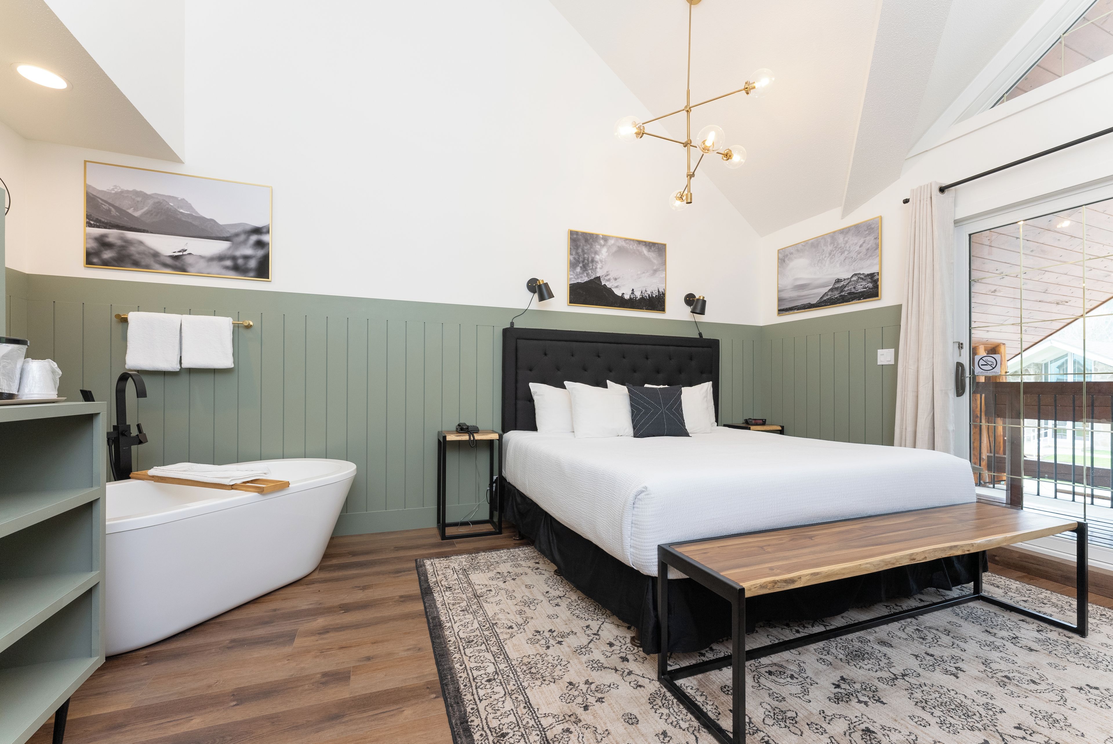 A modern bedroom with a large bed, a built-in bench, a toilet, and a shower area.