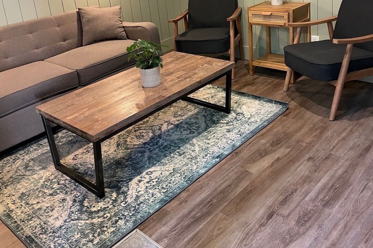 Un salon comprenant un canapé, deux fauteuils, une table basse, un tapis et des tableaux encadrés accrochés au mur.