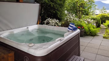 Un jacuzzi con un banco de madera y vistas a un jardín con diversas plantas y flores.