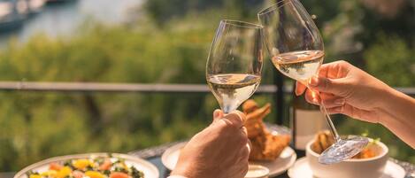 A dining table with plates of food, a bowl of soup, and a glass of white wine.