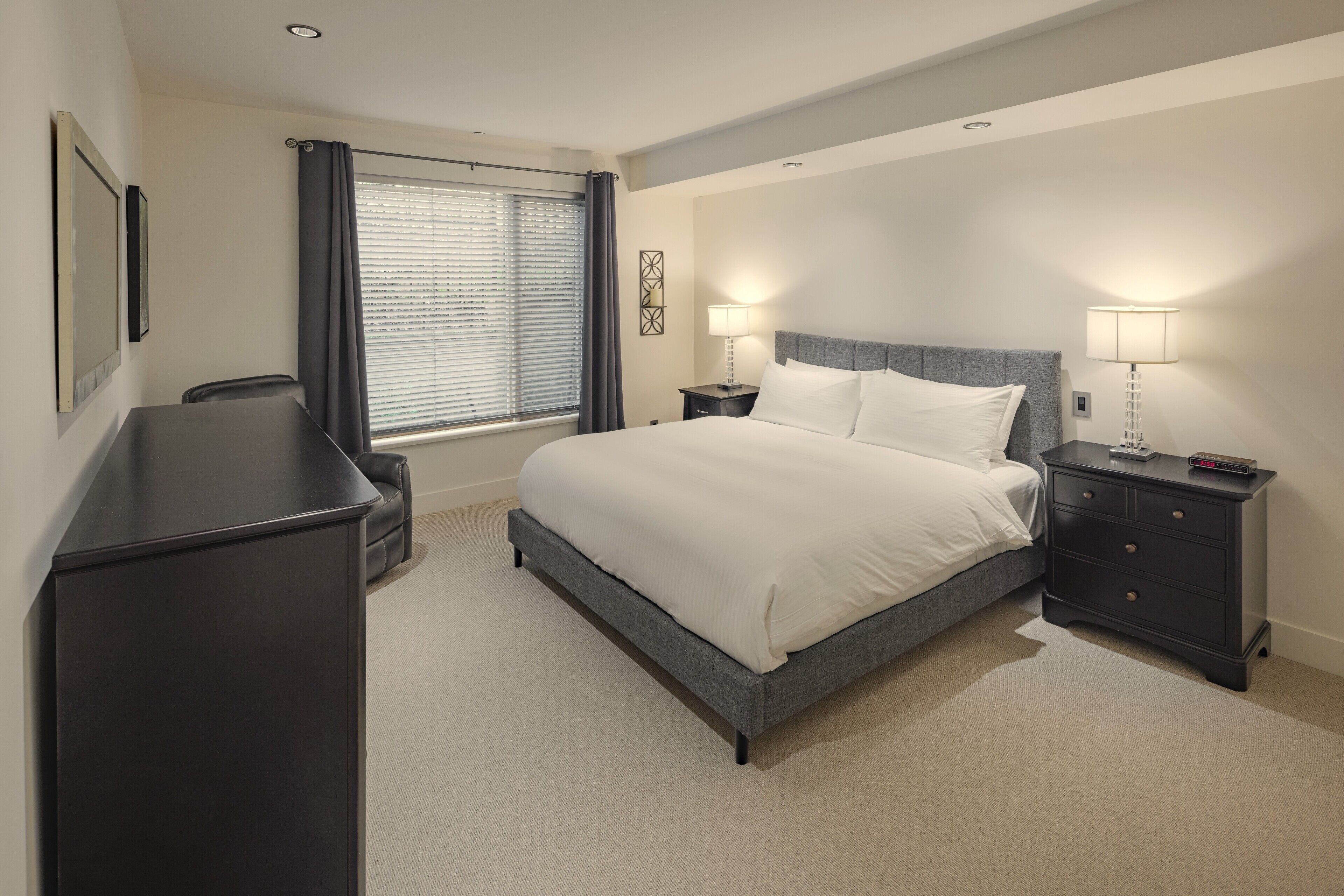 Een hotelkamer met een bed, nachtkastjes, een bureau en een raam met gordijnen.