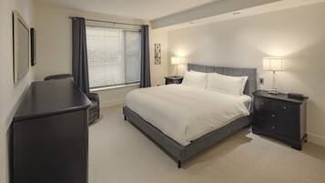 Een hotelkamer met een bed, nachtkastjes, een bureau en een raam met gordijnen.