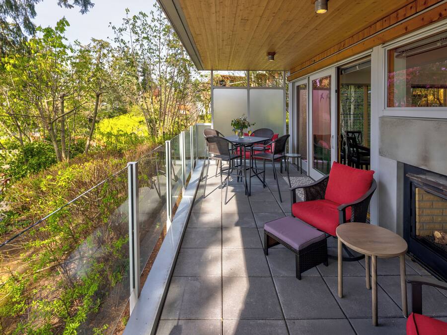 A balcony with outdoor furniture, a glass railing, and a fireplace.