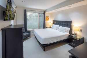 A modern hotel room with a large bed, bedside tables, a desk, and a TV.
