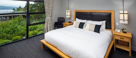 Ein Hotelzimmer mit einem großen Bett, einem Schreibtisch, einem Stuhl und Blick auf Grünflächen und Wasser.