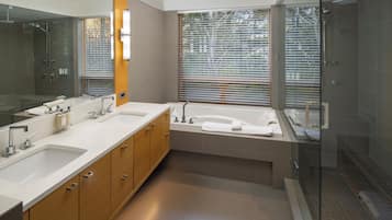 Un baño moderno con un espejo grande, lavamanos dobles, una bañera y una zona de ducha con mampara de vidrio.