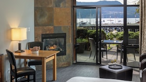 Een hotelkamer met een open haard, een eethoek en een balkon met uitzicht op het water.