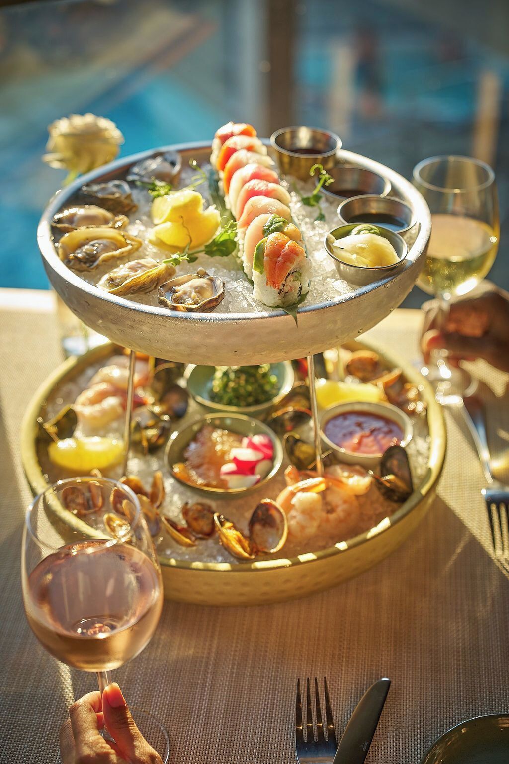 A seafood platter with various types of seafood and sides, accompanied by a glass of white wine.