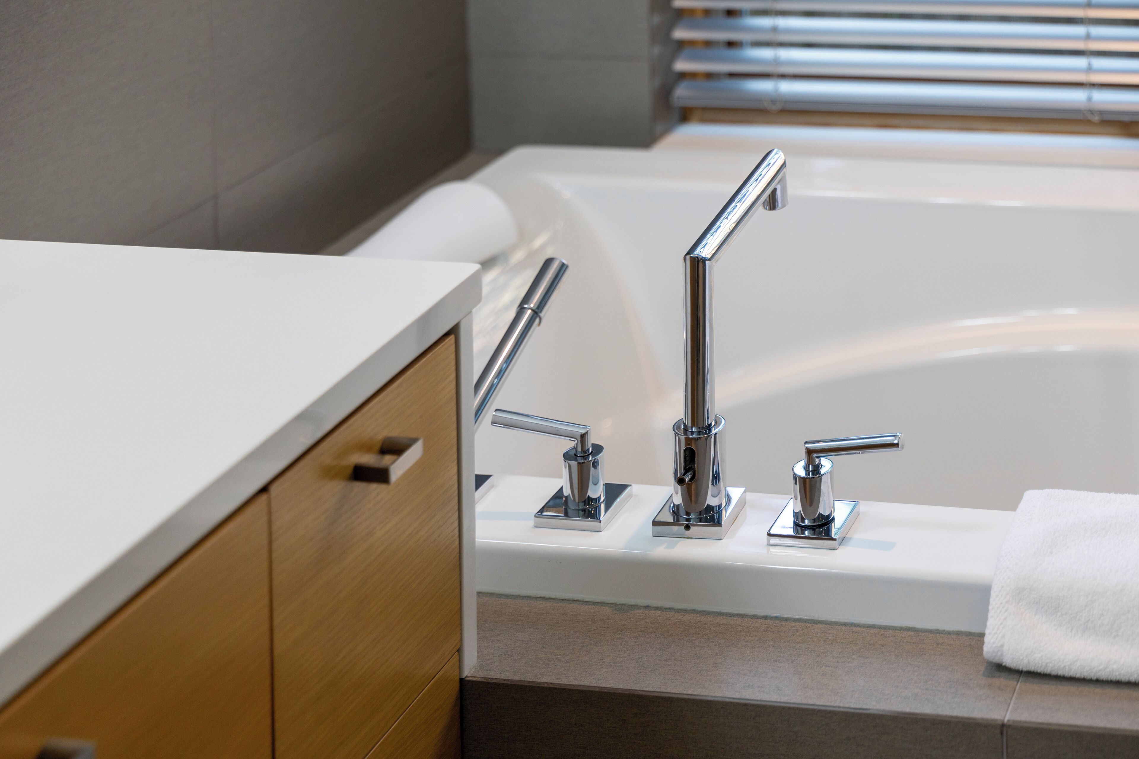Un baño moderno con una bañera blanca, grifería cromada y muebles de madera.