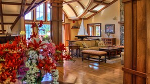 A spacious living room with a high ceiling, wooden beams, and large windows. - Poets Cove Resort & Spa (Pender Island)