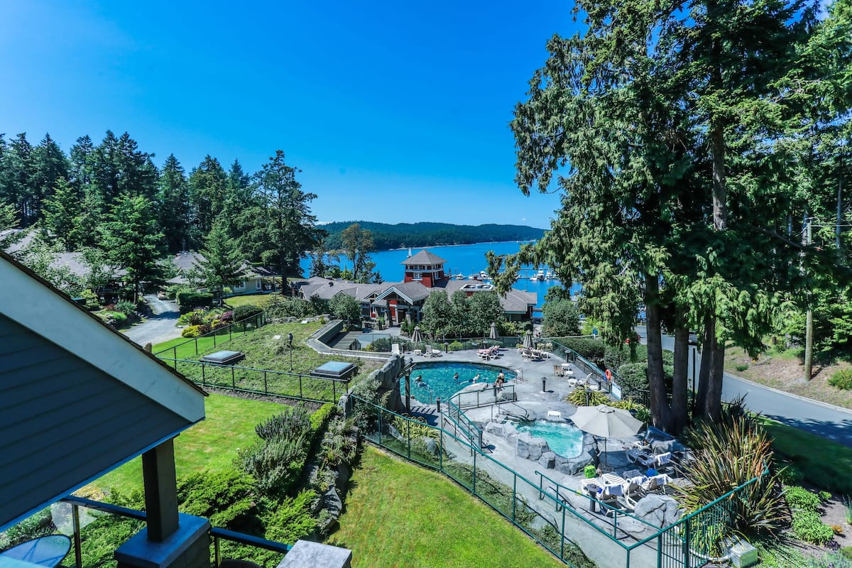 A residential property with a swimming pool, a gazebo, and a view of a lake.