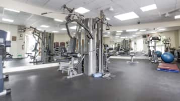 A gym with various exercise machines, mirrors, and a blue exercise ball.