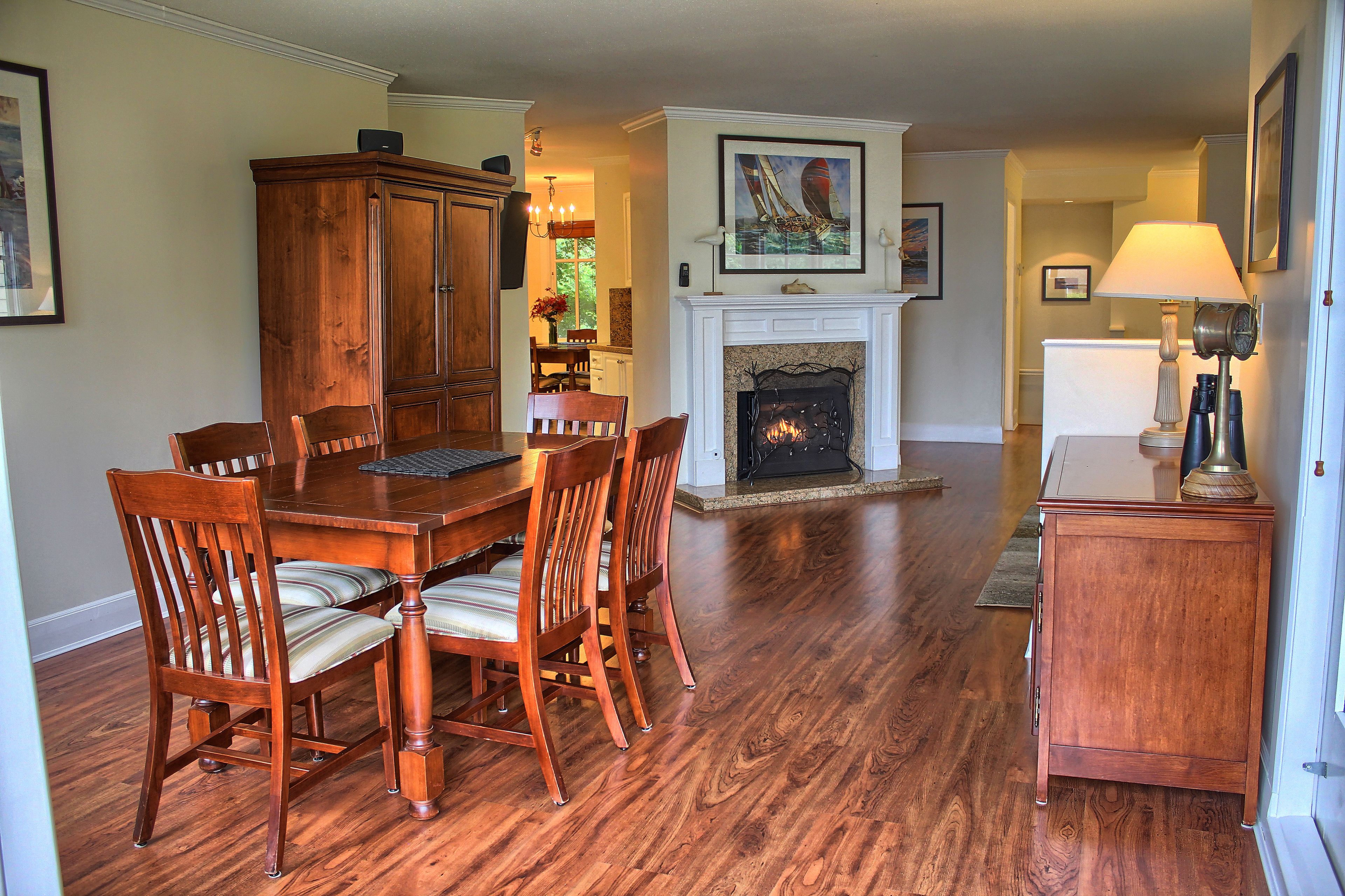 A dining area with a wooden table and chairs, a fireplace, and a lamp.