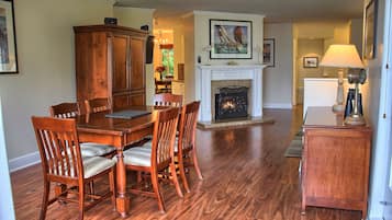 A dining area with a wooden table and chairs, a fireplace, and a lamp.