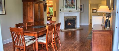 A dining area with a wooden table and chairs, a fireplace, and a lamp.