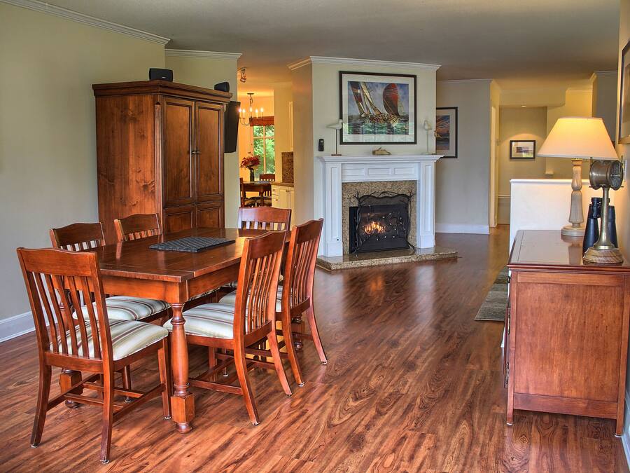 A dining area with a wooden table and chairs, a fireplace, and a lamp.