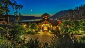 A lodge with a central tower, a covered porch, and a view of a lake at dusk. - Poets Cove Resort & Spa (Pender Island)