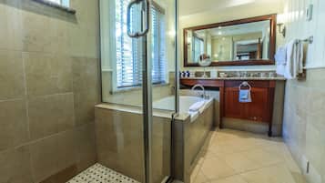Un baño moderno con cabina de ducha de vidrio, bañera, lavabo con tocador y un espejo grande sobre el lavabo.
