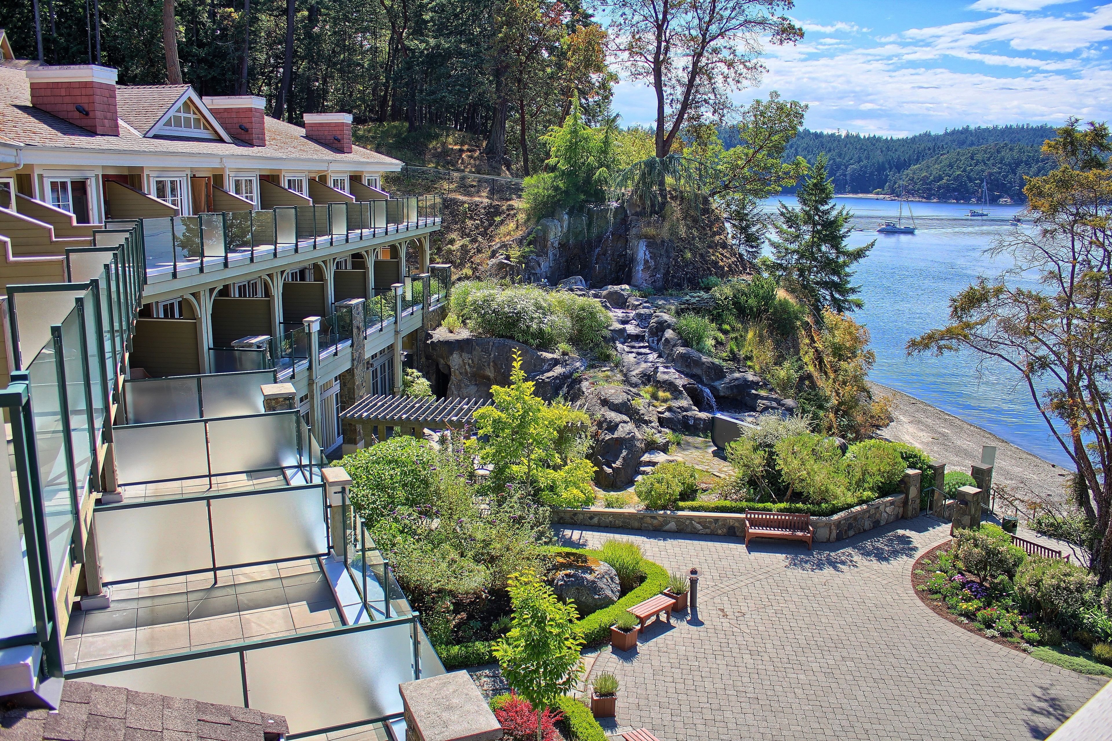 Ein Hotel mit schöner Aussicht auf einen See, einem Felsengarten und einer Holzterrasse.