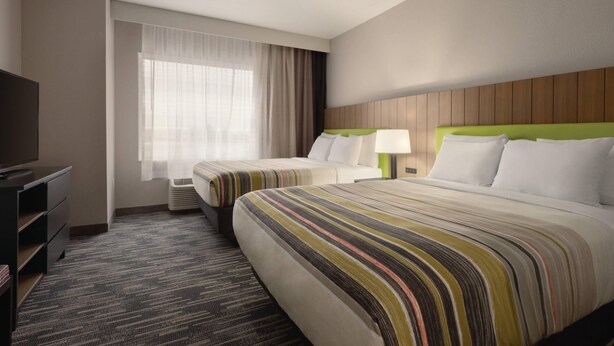 A hotel room with two beds, a TV, a desk, and a window with curtains. - Country Inn & Suites by Radisson, Champaign North, IL (Champaign)