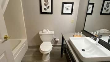 A bathroom with a bathtub, toilet, and sink. There are framed pictures on the wall.