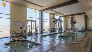 An indoor pool with clear water, a lifeguard chair, and a palm tree.