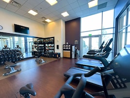 A gym with treadmills, weight machines, and a mirror wall.