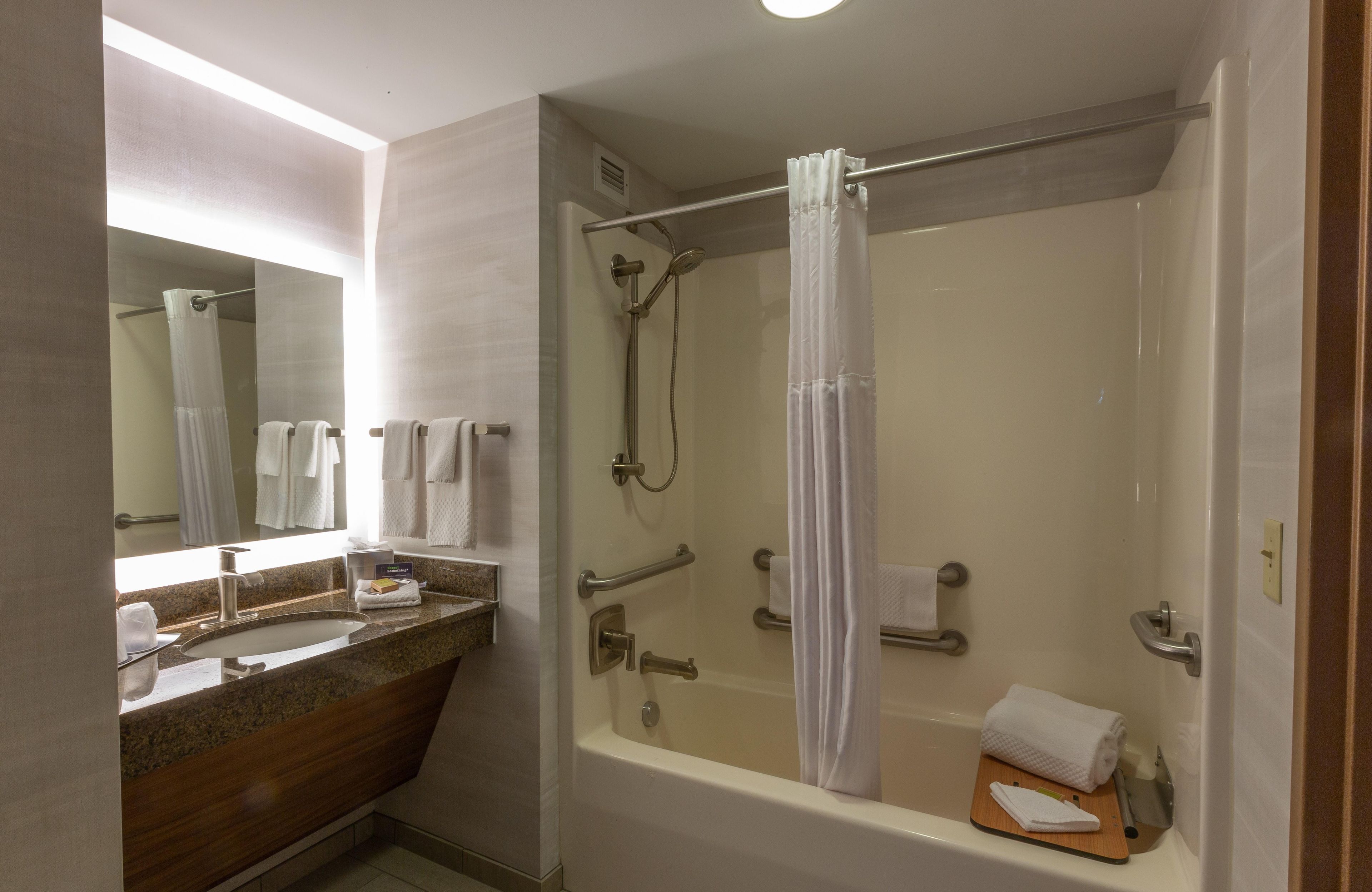 Un bagno moderno con doccia vetrata, un mobile lavabo con piano in granito e uno specchio grande.
