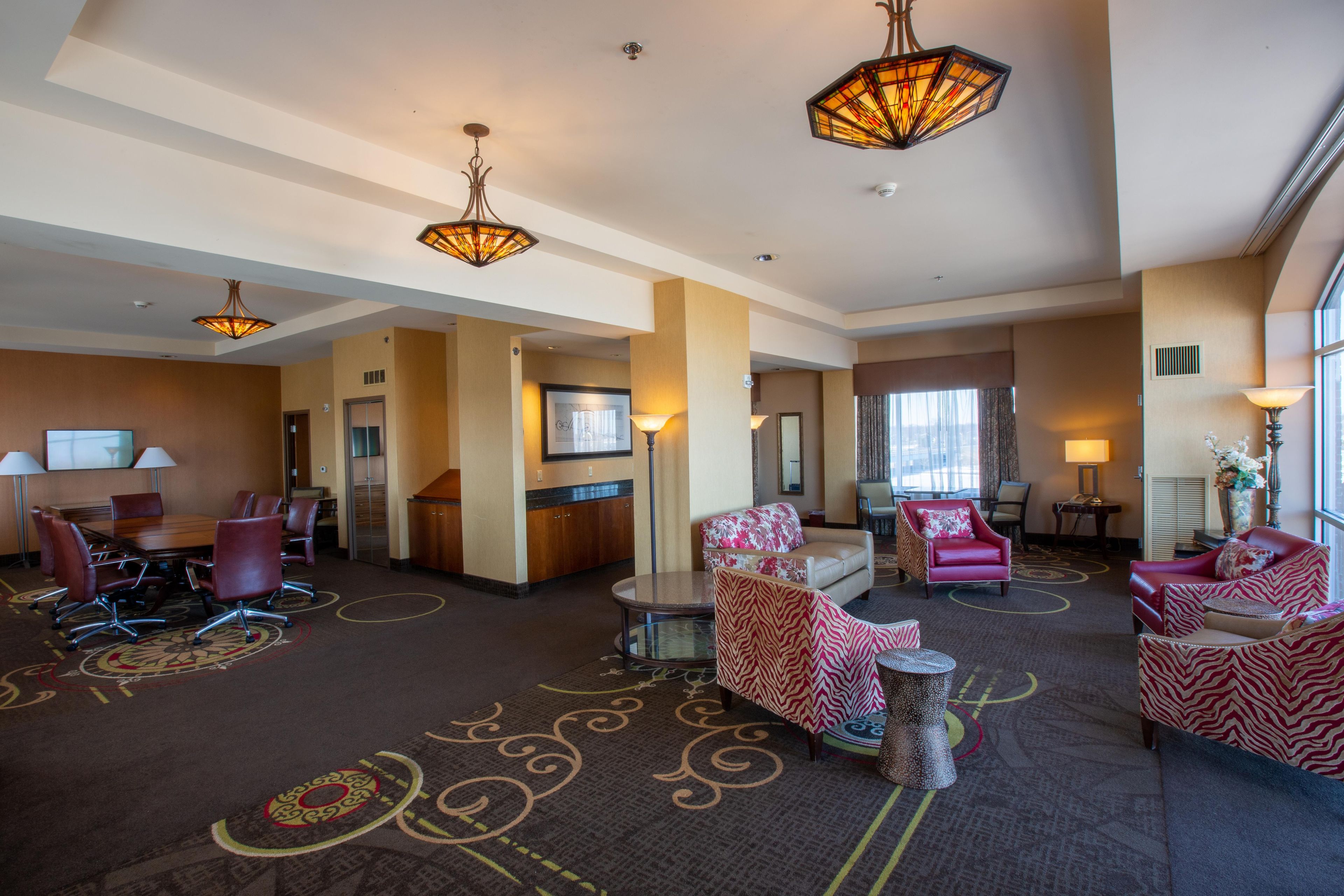 A hotel lobby with a conference room, seating area, and a large window.