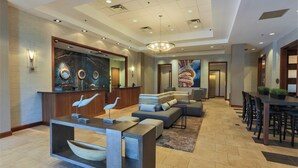 A hotel lobby with a reception desk, seating area, and a large painting.