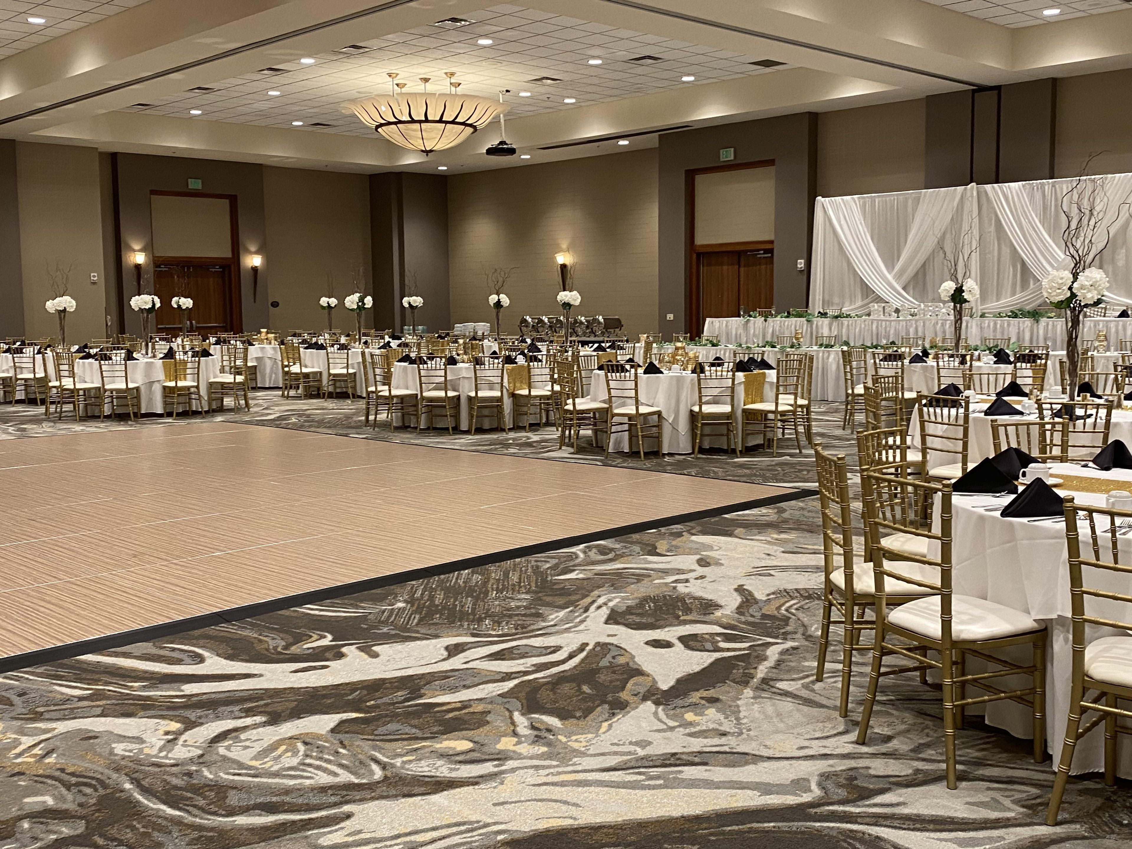 A banquet hall with round tables, chairs, and a dance floor.