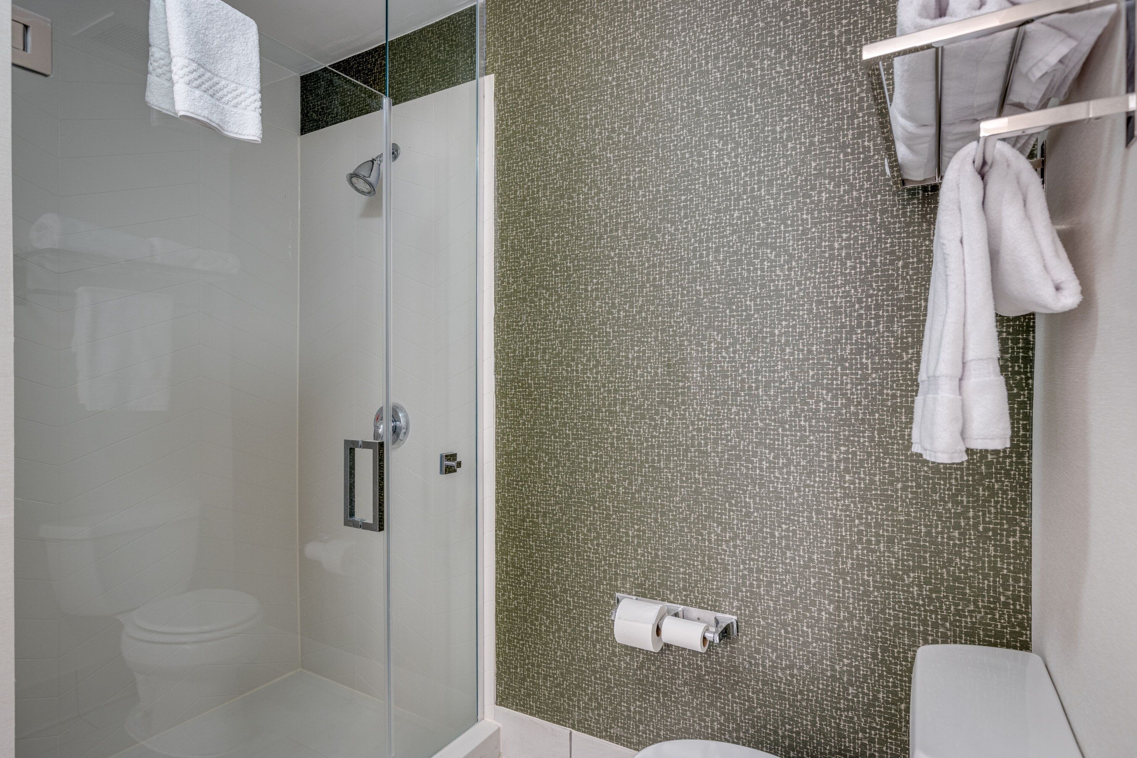 A modern bathroom with a glass shower enclosure, a toilet, and a towel rack.