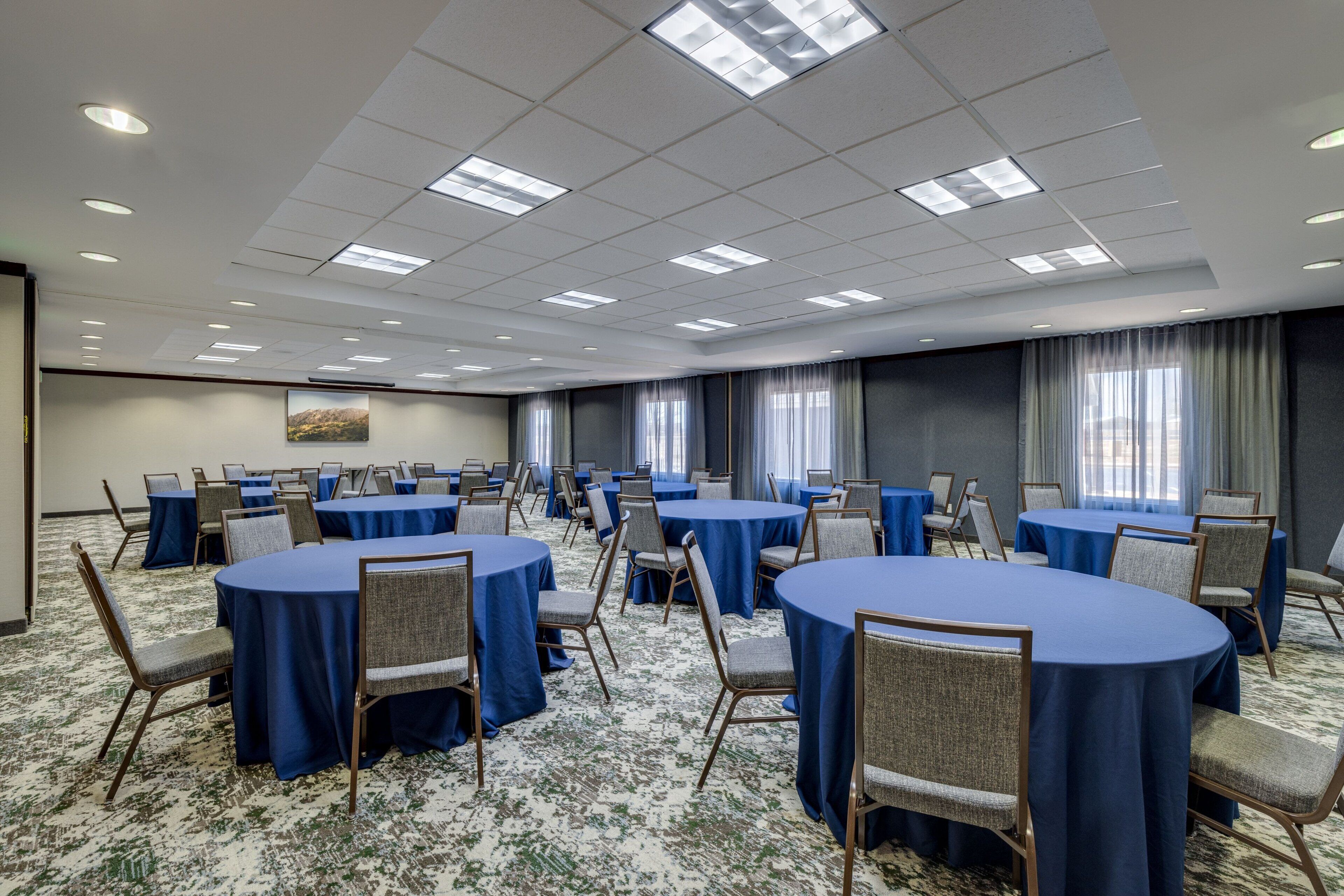 A conference room with round tables, chairs, and blue tablecloths.