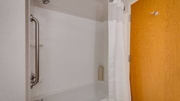 A bathroom with a white bathtub, a wooden door, and a shower with a curtain.