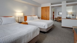 Een hotelkamer met twee bedden, een bureau, een stoel en een kledingkast.