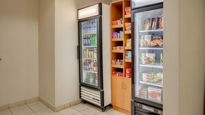 Een automaatgedeelte met een koelkast vol drankjes en snacks, en een houten kast met verpakte etenswaren.