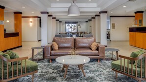 Een ruime lobby met een leren bank, een rond bijzettafeltje en een receptiebalie.