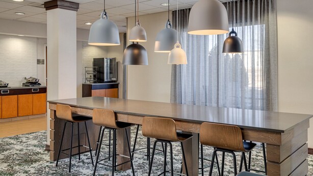 Een moderne keuken met een groot eiland, barkrukken, hanglampen en uitzicht op de eethoek.