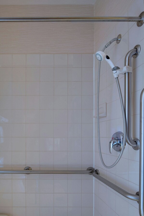 A shower area with a handheld showerhead and a wall-mounted faucet. - Fairfield Inn and Suites by Marriott Lawton (Lawton)
