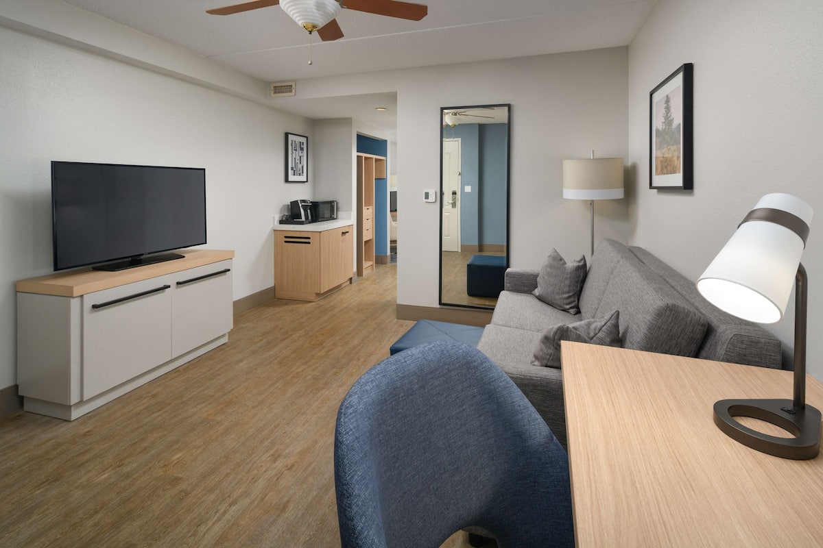 A modern living room with a flat-screen TV, a sofa, a coffee table, and a lamp.