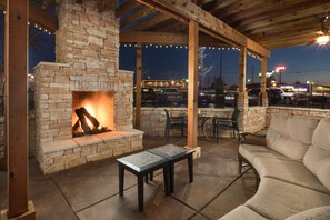 An outdoor patio area with a stone fireplace, wooden pergola, and a cushioned seating area. - Hilton Garden Inn Chattanooga/Hamilton Place (Chattanooga)